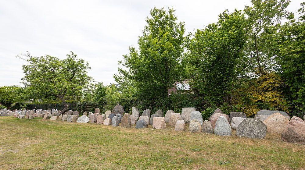 Ein Friedhof mit vielen Gräbern und Bäumen im Hintergrund.