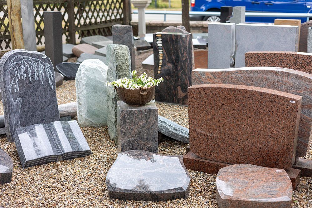 Ein Haufen Grabsteine ​​liegen auf Kies auf einem Friedhof
