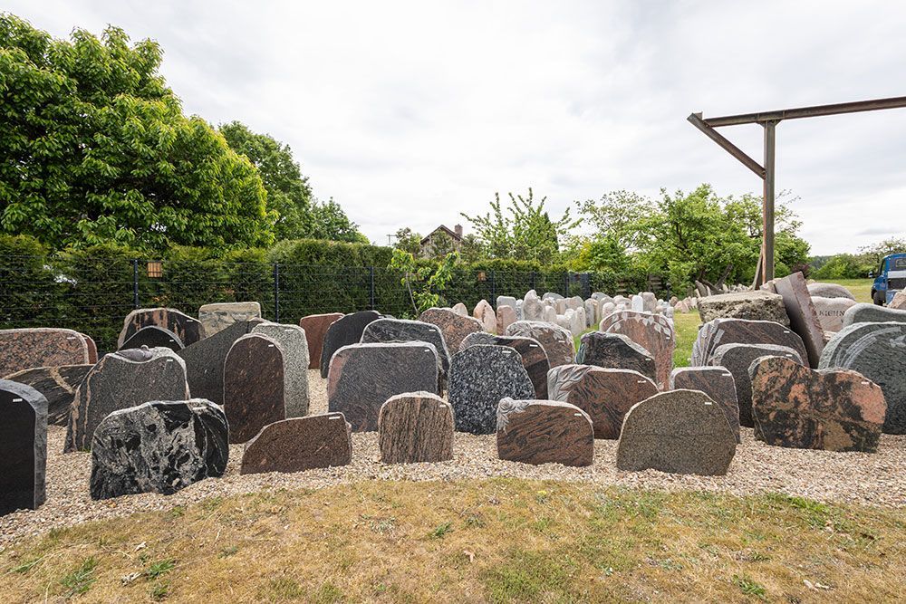 Auf einem grasbedeckten Feld stehen mehrere Grabsteine.