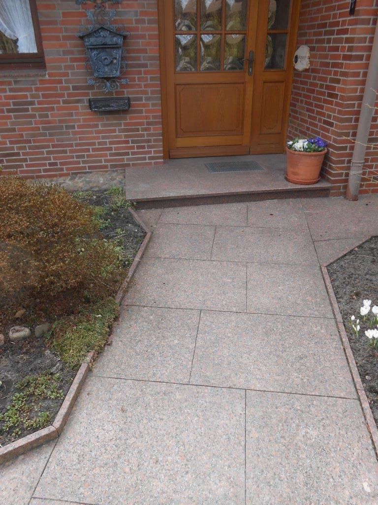 Ein Backsteingebäude mit einer Holztür und einem Steinweg, der dorthin führt.