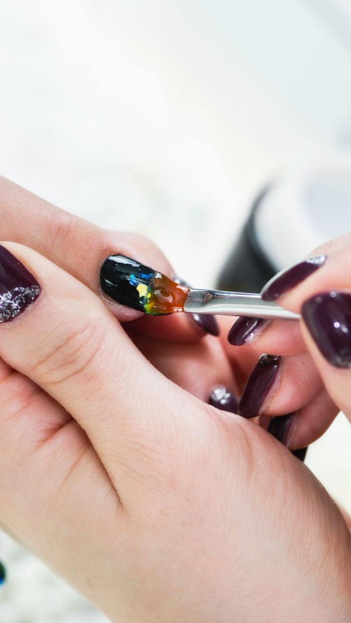 Les ongles d'une personne sont peints de plusieurs couleurs par une autre personne dans un cadre de manucure.