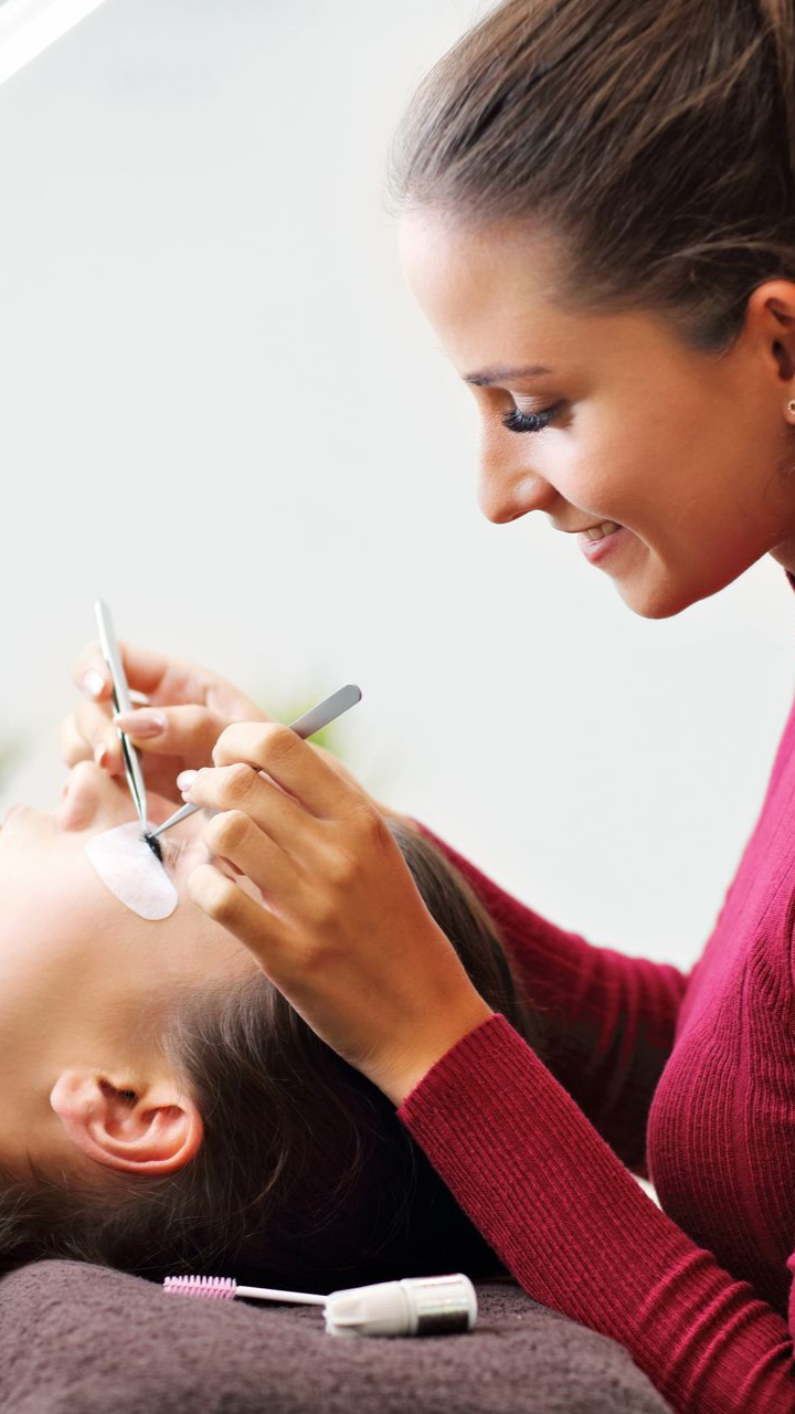 Une femme applique des extensions de cils sur une cliente dans un salon de beauté.