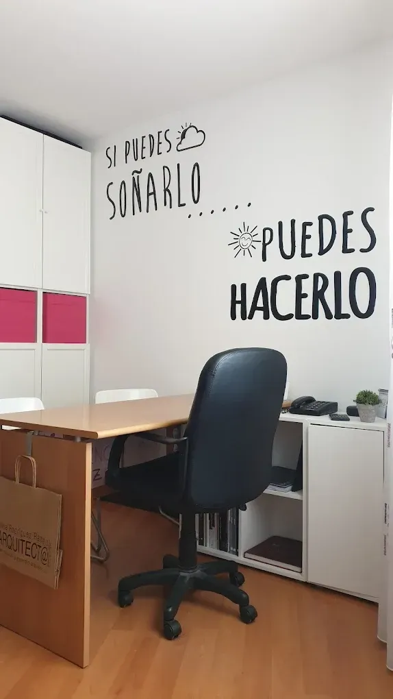 Oficina en casa con escritorio, silla, armario blanco y vinilos decorativos en la pared que dicen “Sí puedes hacerlo”.