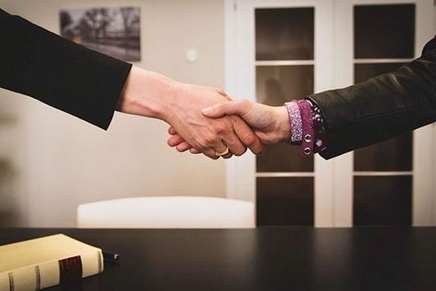 Dos personas se dan la mano sobre una mesa.