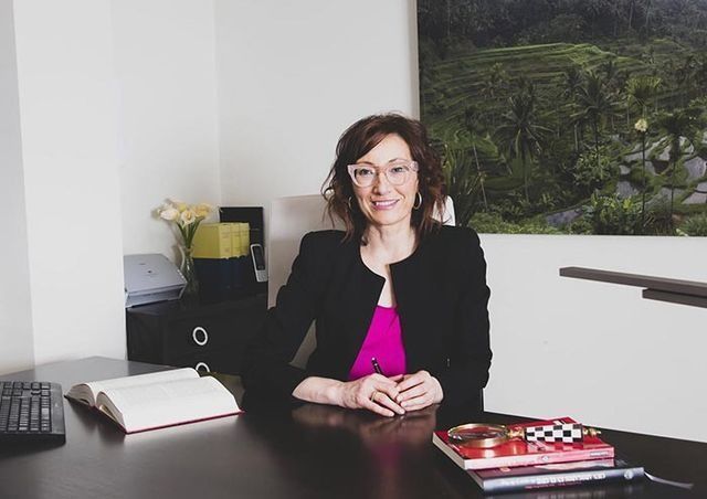 Una mujer está sentada en un escritorio con un libro encima.