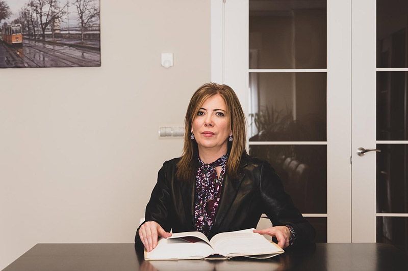 Una mujer está sentada en una mesa leyendo un libro.