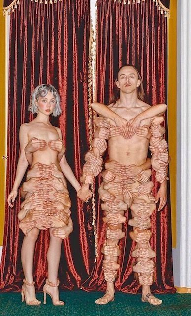 Un hombre y una mujer están parados uno al lado del otro vistiendo ropa hecha de carne.