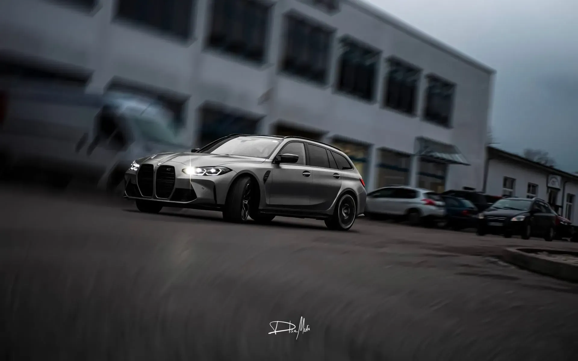 Vor einem Gebäude parkt ein silberner BMW M3 Touring.