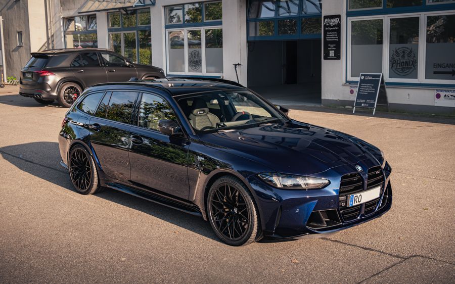 Vor einem Gebäude parkt ein blauer BMW M3 Touring.