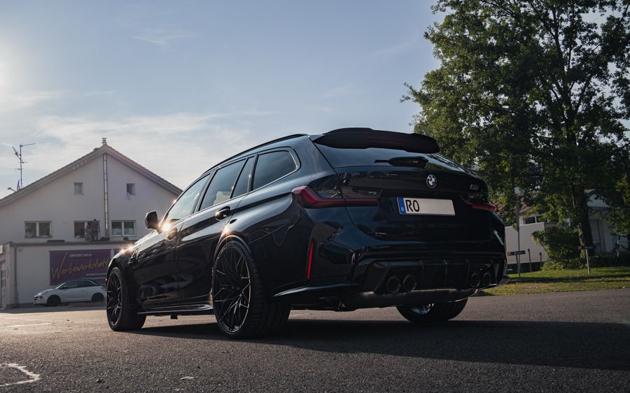 Ein schwarzer BMW M3 Touring steht am Straßenrand vor einem Haus.