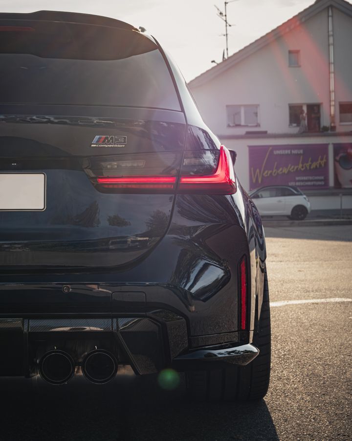 Ein schwarzes Auto steht auf einem Parkplatz vor einem Gebäude.