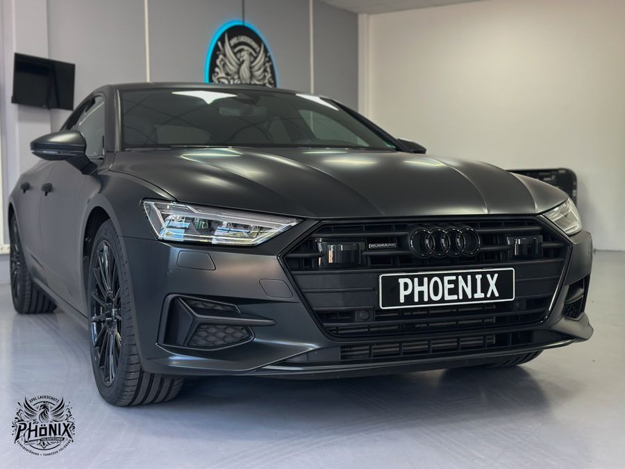 In einer Garage parkt ein schwarzer Audi A7 mit einem Nummernschild mit der Aufschrift „Phoenix“.