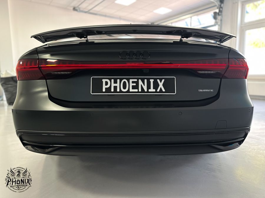Ein schwarzes Auto mit einem Nummernschild mit der Aufschrift „Phoenix“ steht in einer Garage.