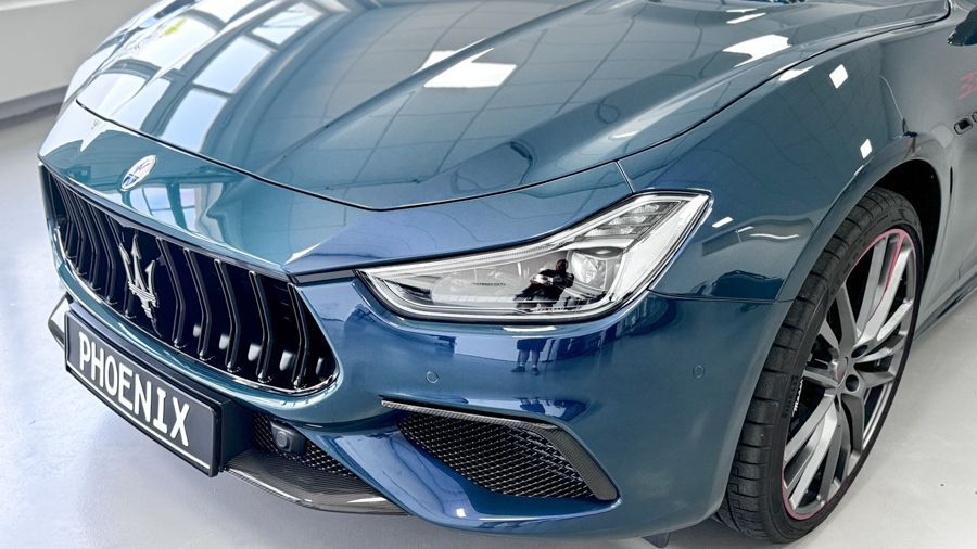 Ein blauer Maserati Ghibli steht in einem Ausstellungsraum.