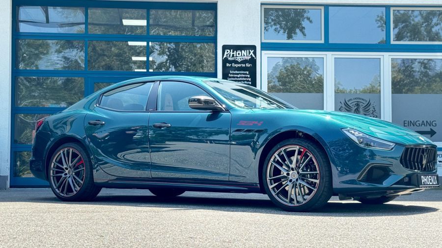 Ein grüner Maserati Ghibli steht vor einem Garagentor.