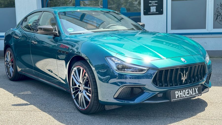Ein grüner Maserati Ghibli steht vor einem Gebäude.