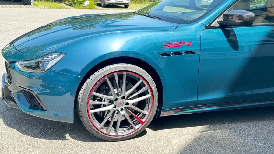 Ein blaues Auto mit roten Felgen steht am Straßenrand.