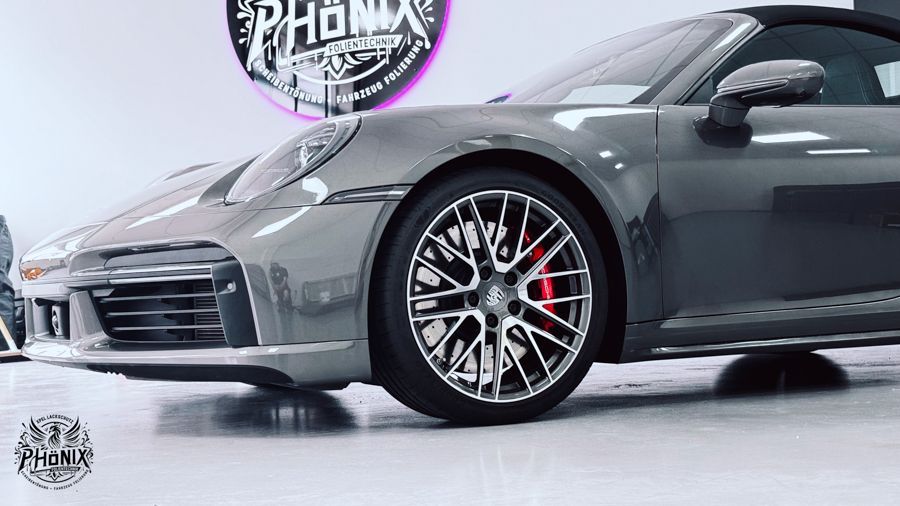 Ein grauer Porsche 911 Carrera steht in einer Garage.