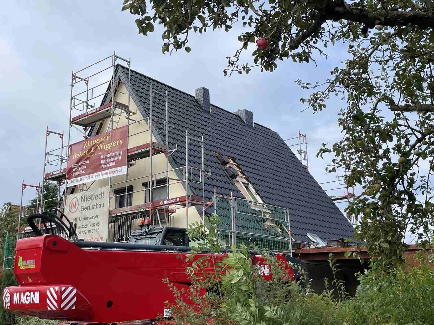 Ein roter Kran steht vor einem im Bau befindlichen Gebäude.
