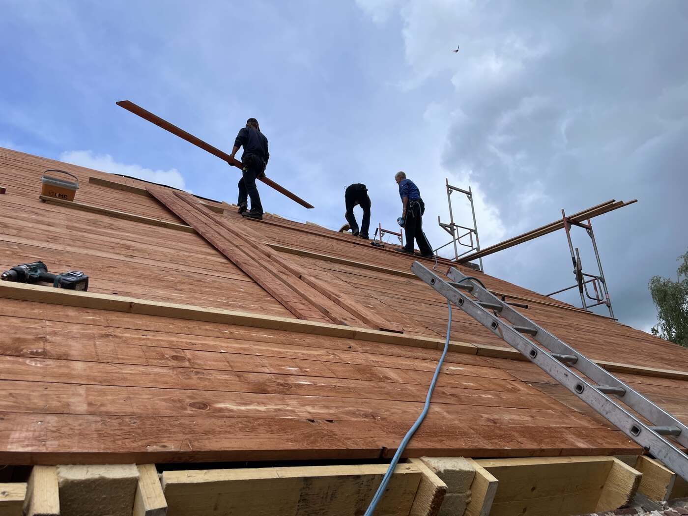 Eine Gruppe Bauarbeiter arbeitet an einem Holzdach.