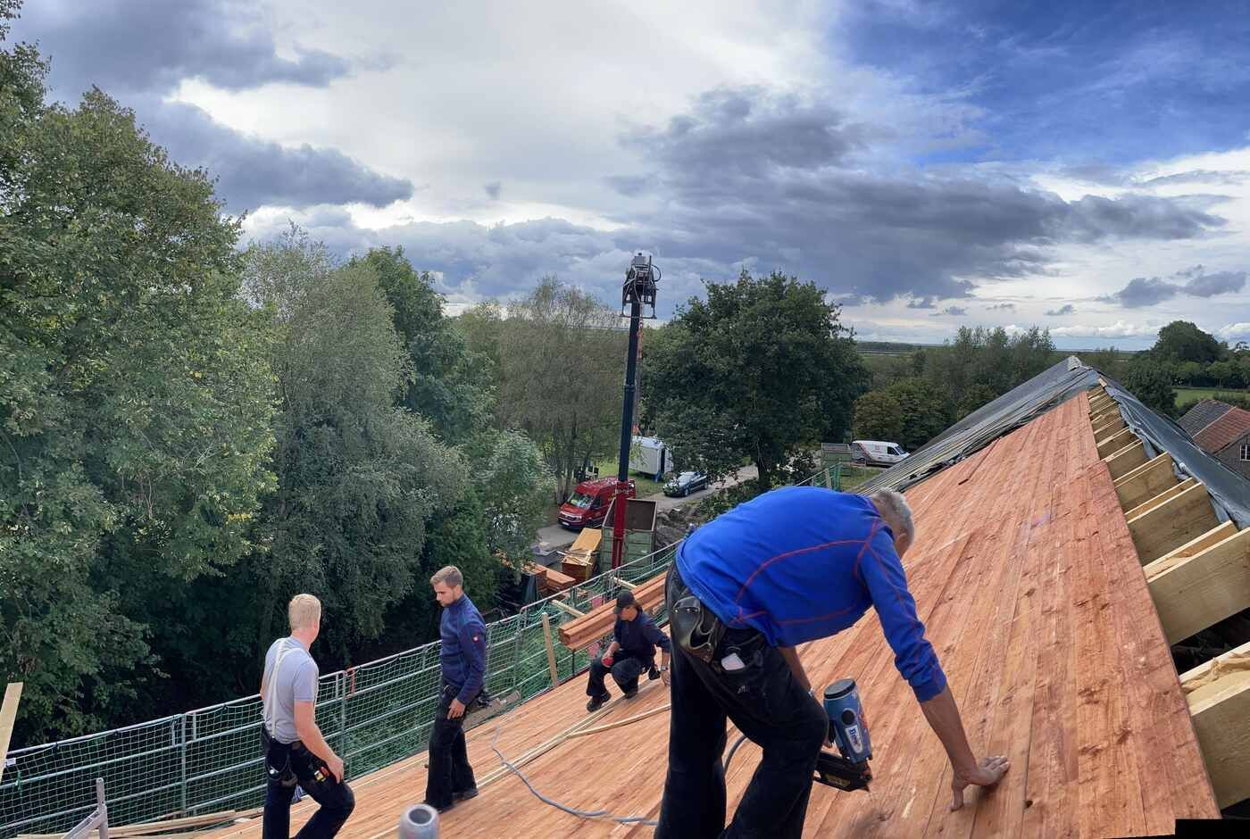 Eine Gruppe von Menschen arbeitet an einem Holzdach.