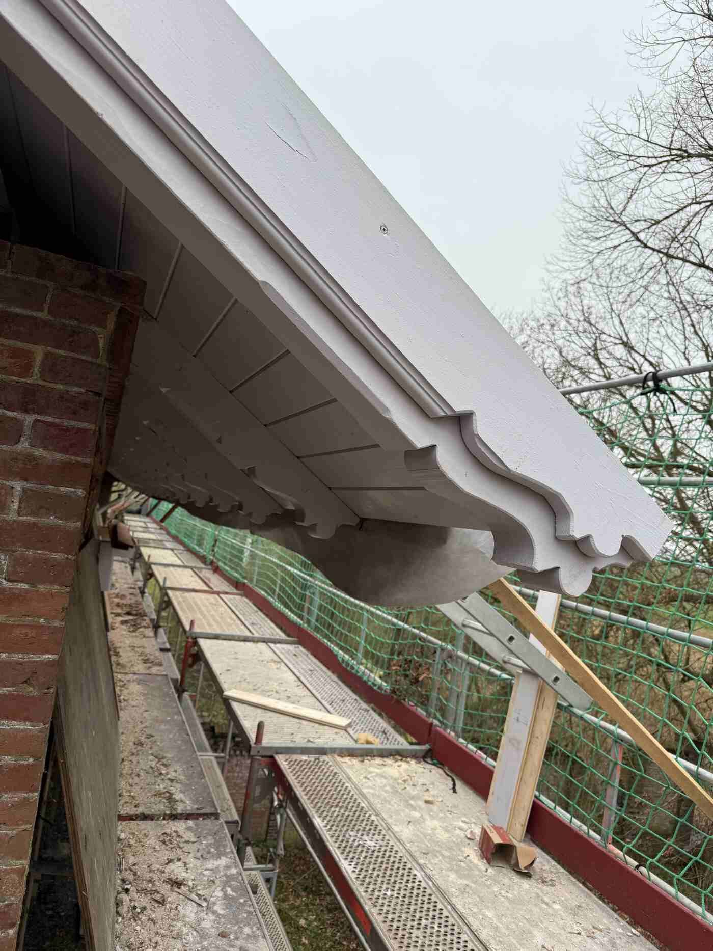 Auf einem Backsteingebäude wird ein Dach mit weißer Zierleiste errichtet.