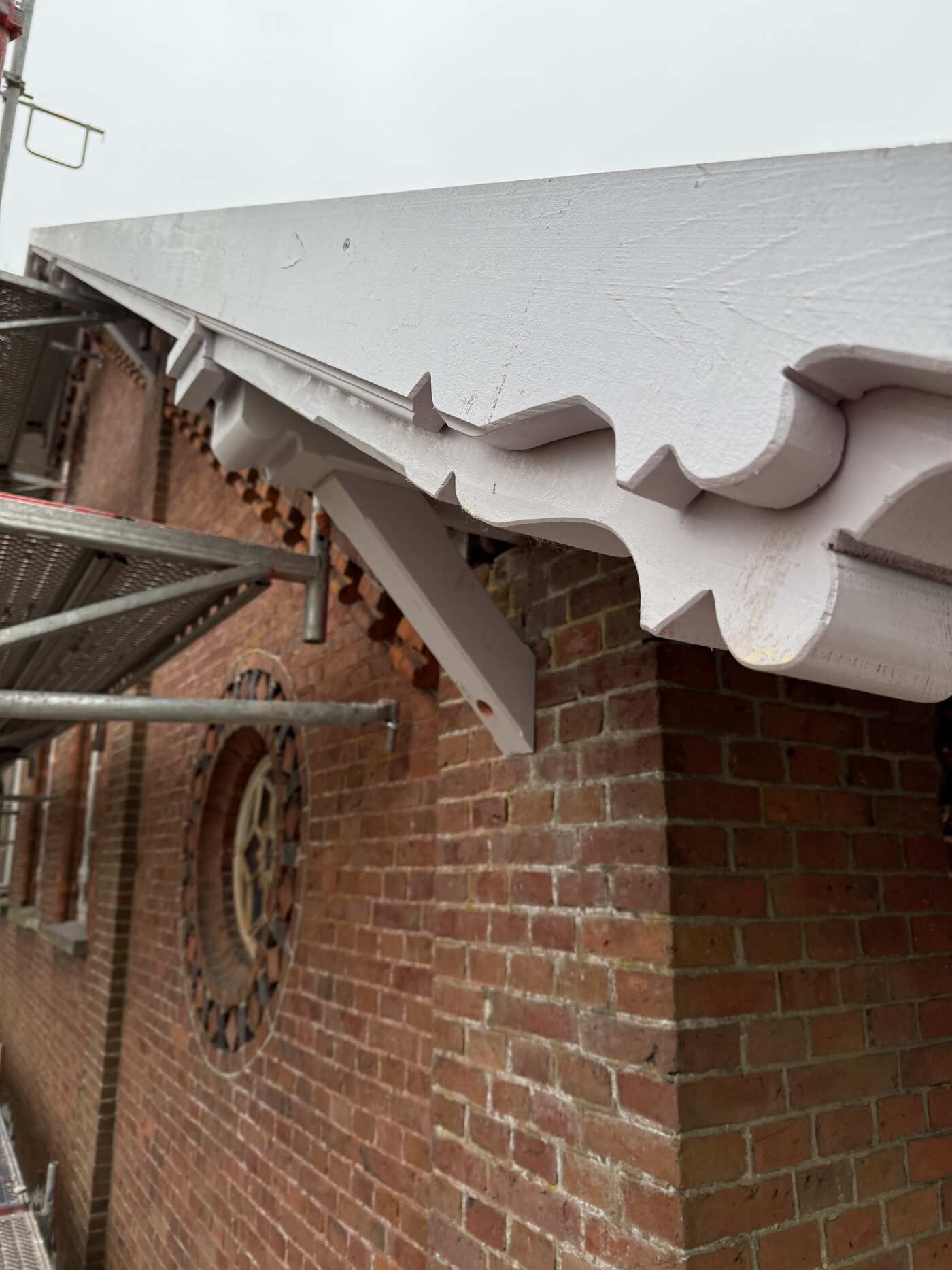 Ein Backsteingebäude mit weißem Dach und einem Gerüst an der Seite.