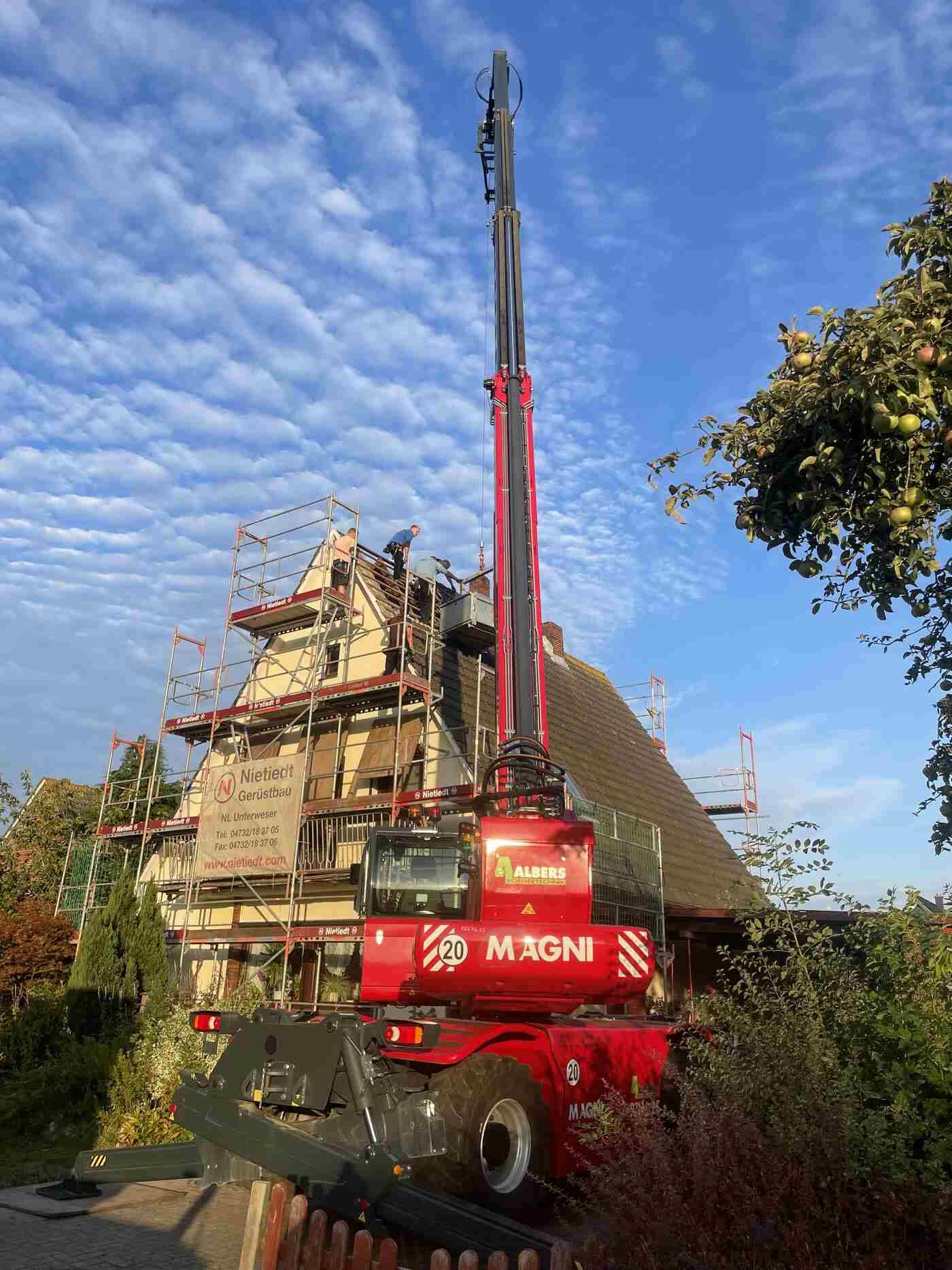 Ein roter Kran steht vor einem im Bau befindlichen Gebäude.