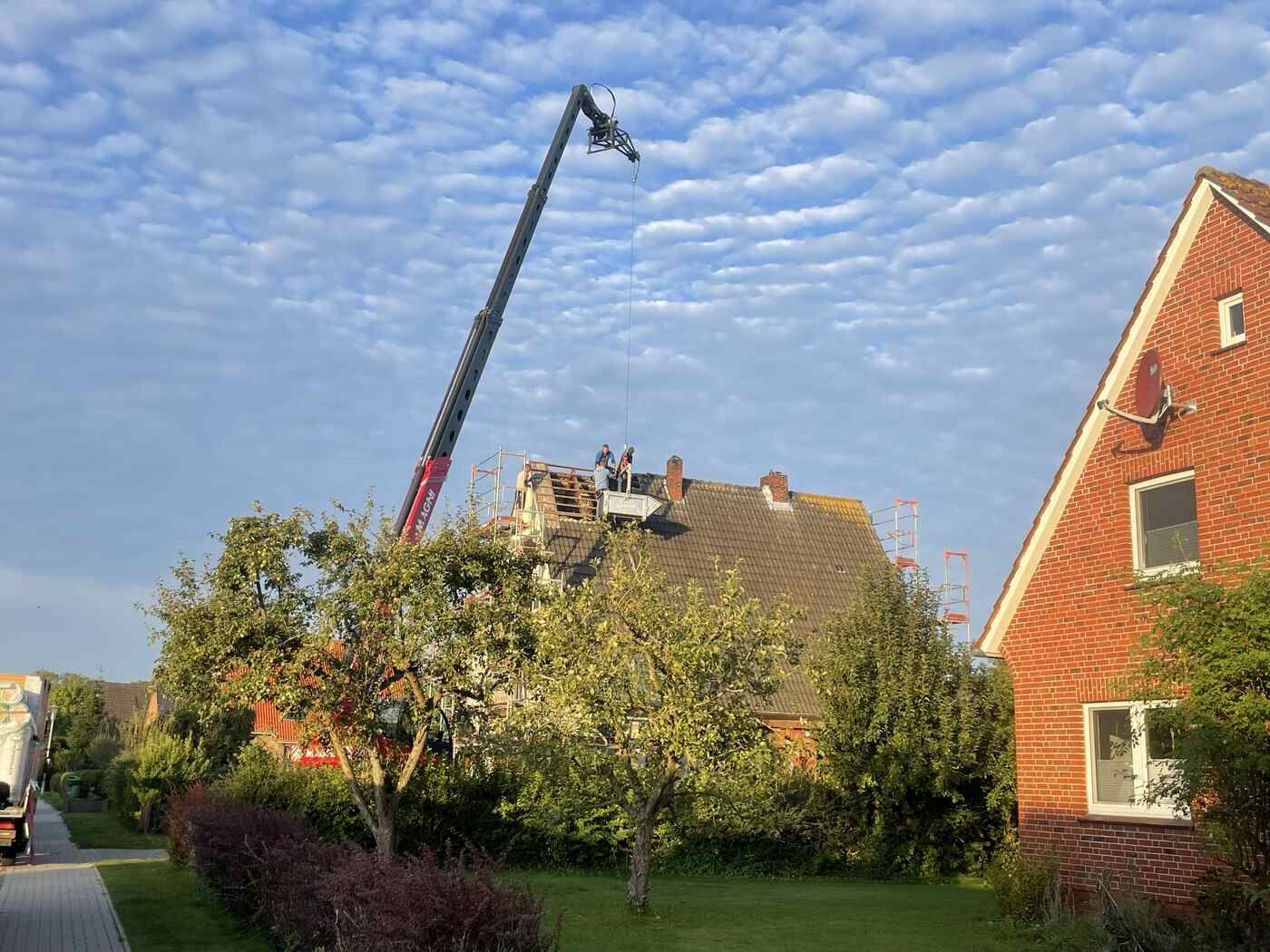 Ein Kran arbeitet auf dem Dach eines Hauses.