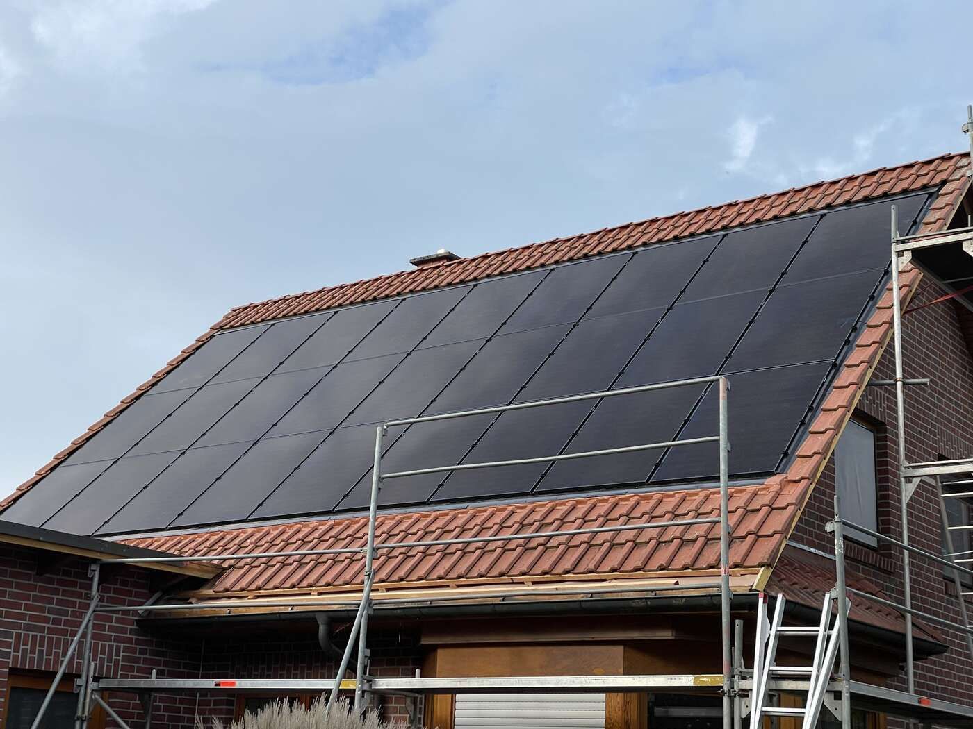Ein Backsteinhaus mit Solarzellen auf dem Dach.