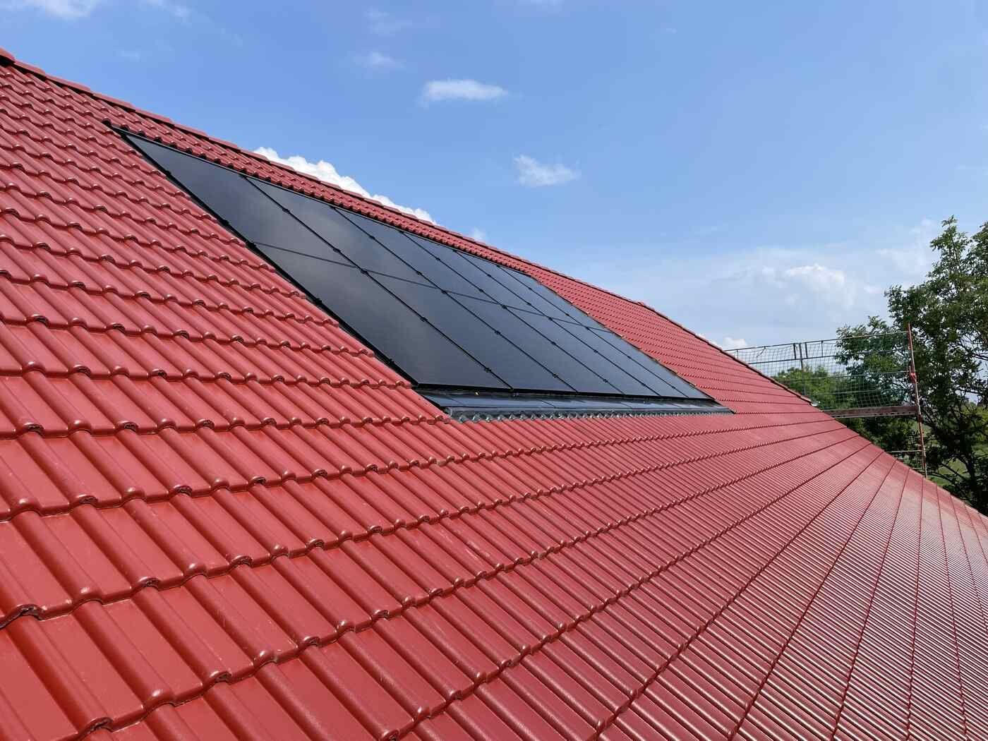 Ein rotes Ziegeldach mit Solarmodulen darauf