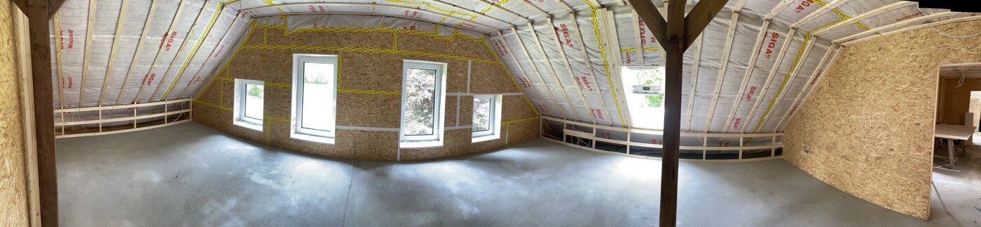 Ein großer Raum mit vielen Fenstern und einer Holzdecke.