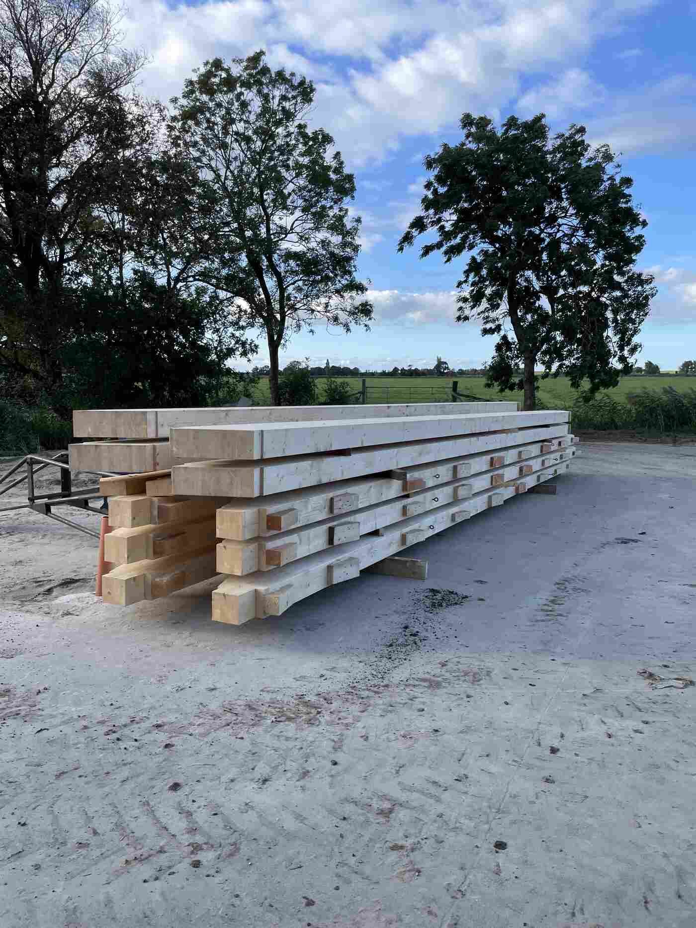 Ein Stapel Holzbalken, die übereinander auf einem Feld liegen.