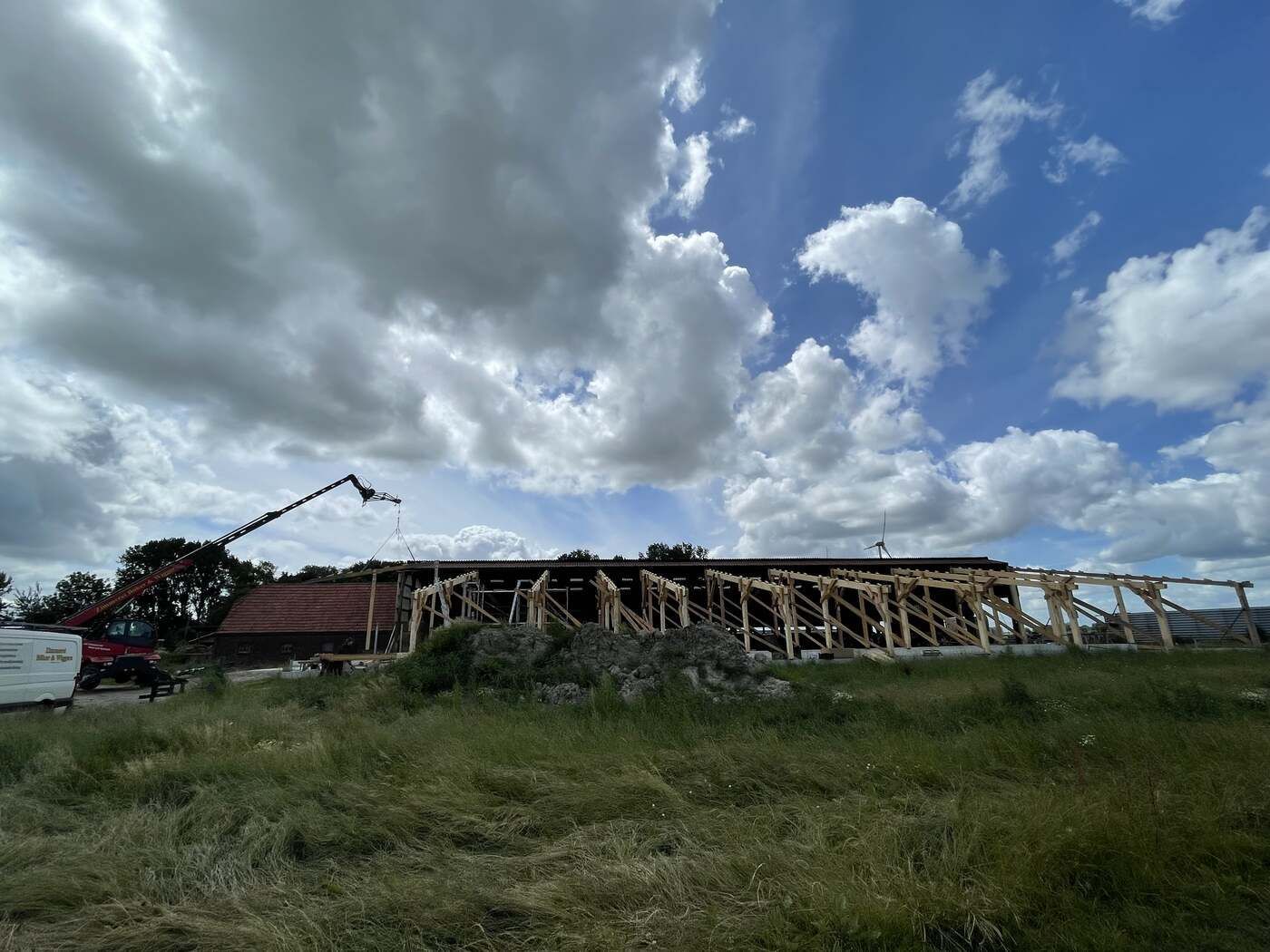 Auf einem Feld wird ein großes Gebäude errichtet. Im Vordergrund steht ein Kran.