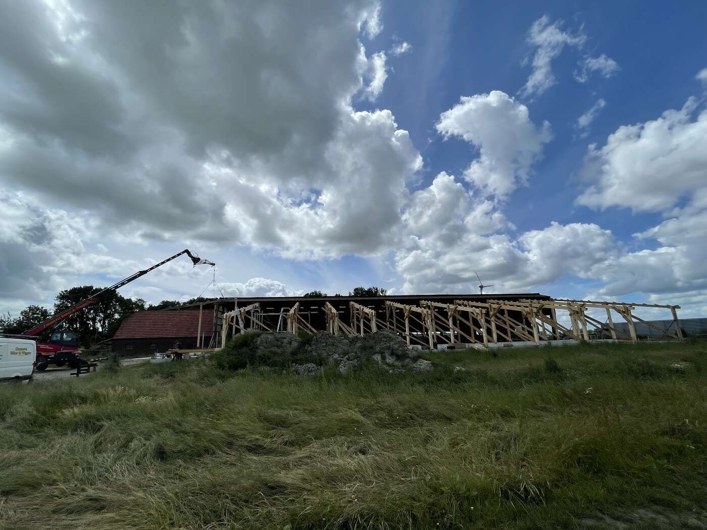 Auf einem Feld wird eine große Holzkonstruktion errichtet.