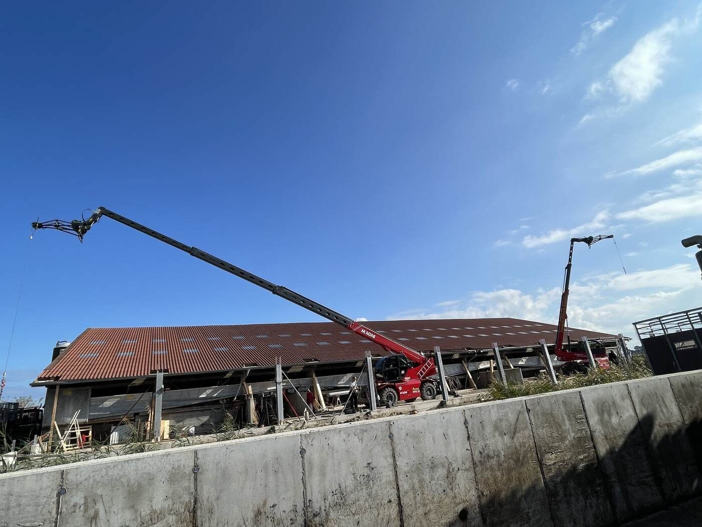 Ein roter Kran steht auf einer Betonmauer vor einem Gebäude.