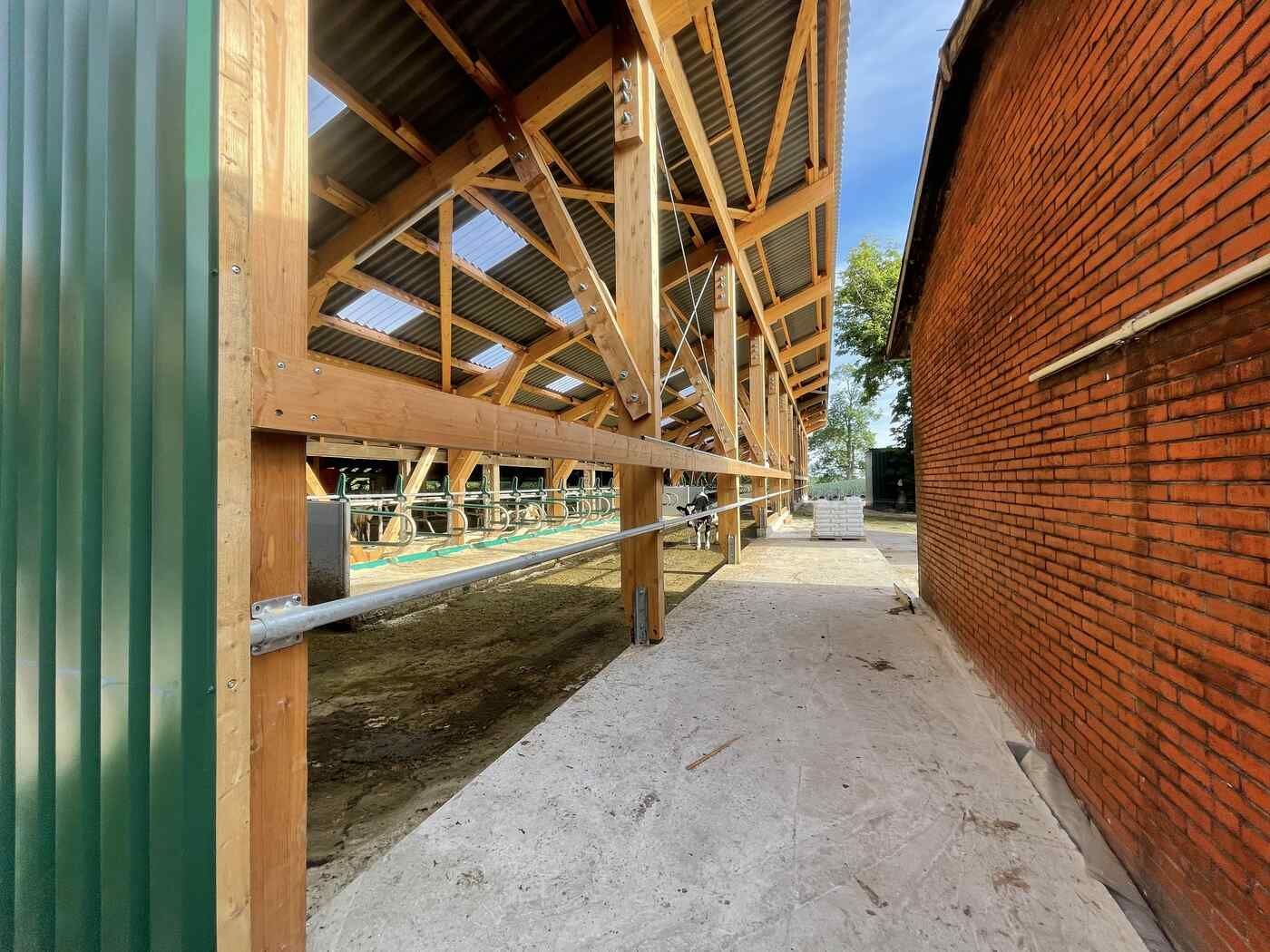 Ein Backsteingebäude mit einem grünen Zaun und einem Holzdach