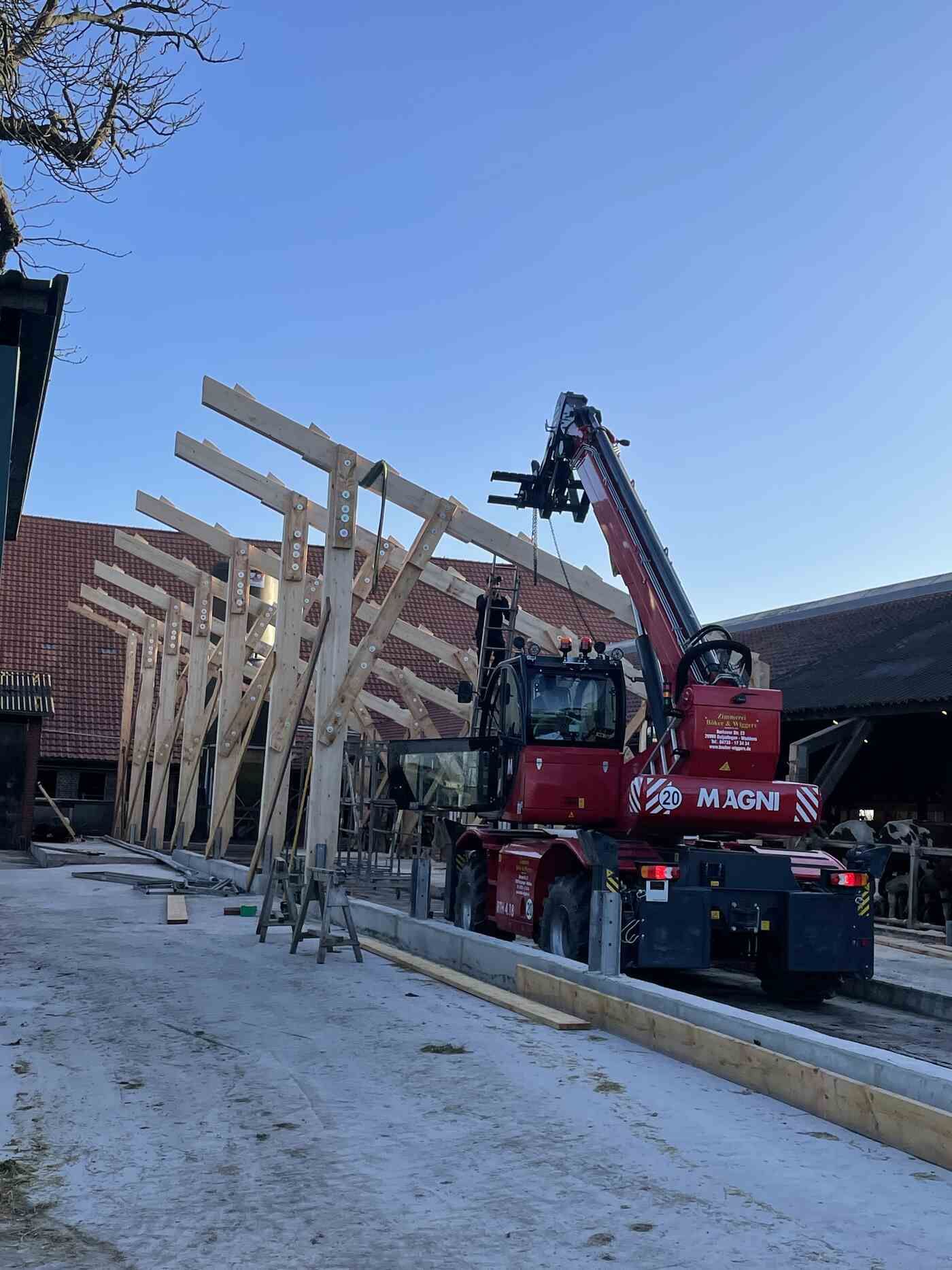 Ein roter Lastwagen mit einem daran befestigten Kran transportiert Holzbalken.