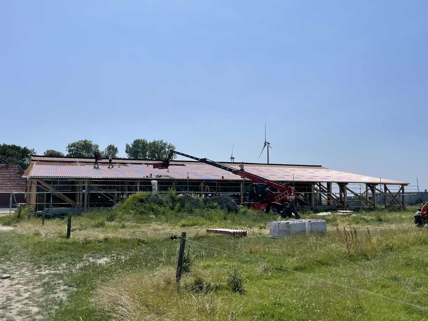 Mit einem Kran wird ein Dach auf einem Gebäude montiert.