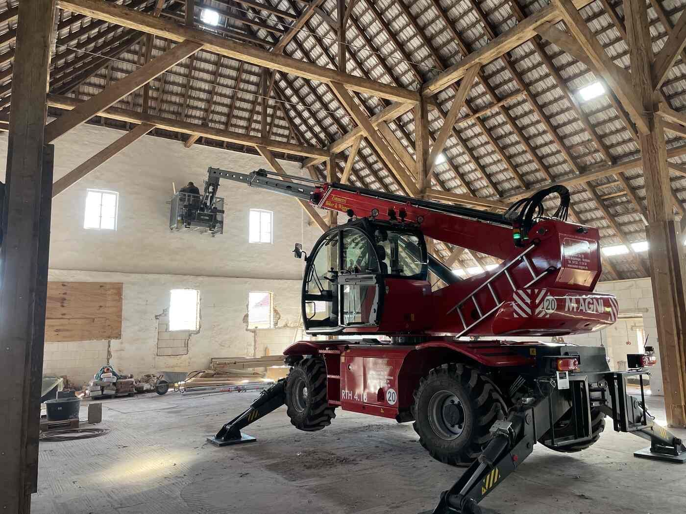 Ein roter Kran steht in einer Scheune unter einem Holzdach.