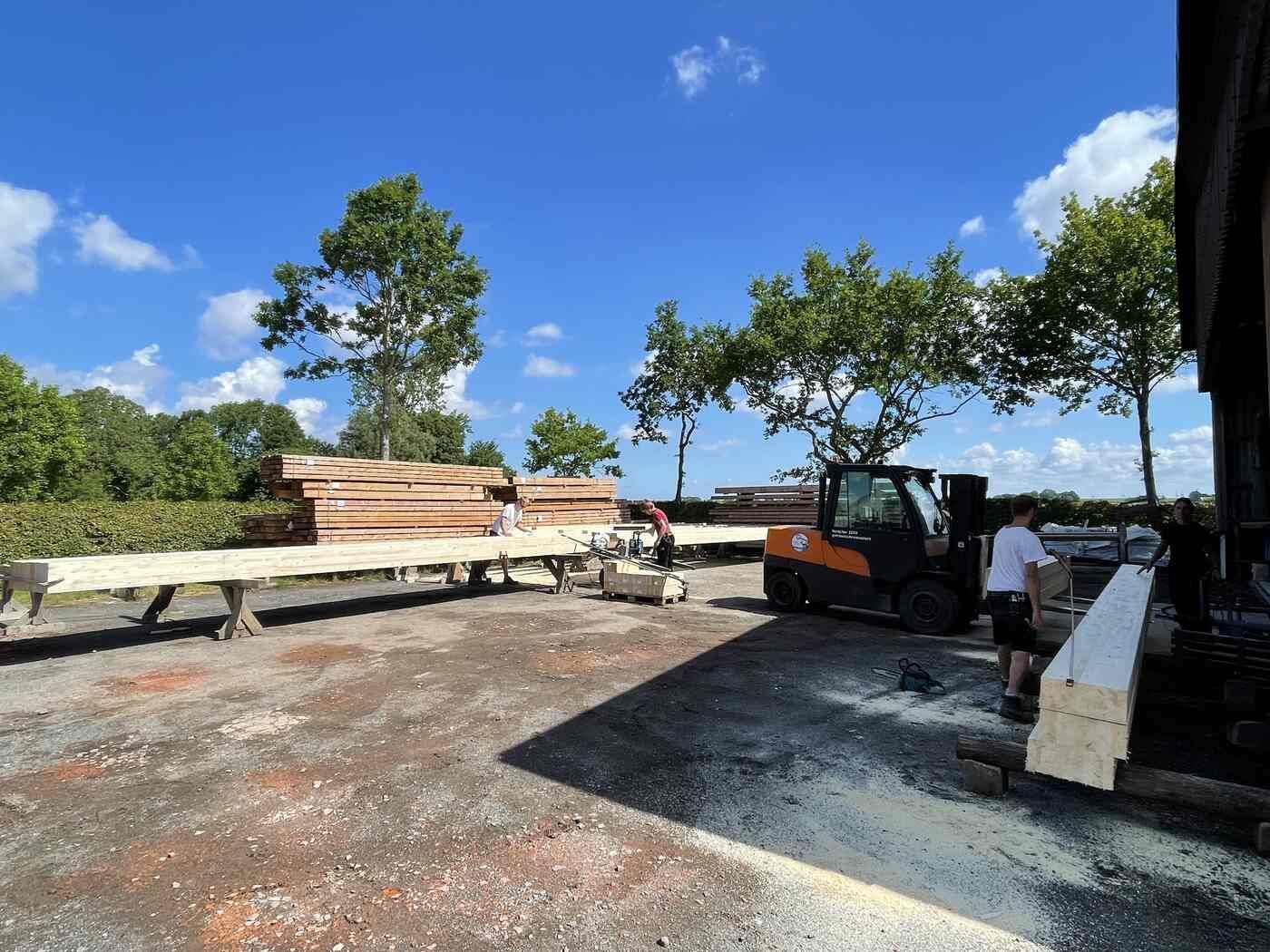 Ein Gabelstapler transportiert einen Stapel Holz in einen Hof.