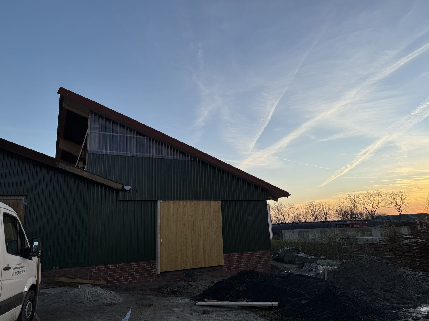 Ein weißer Lieferwagen parkt vor einem grünen Gebäude.