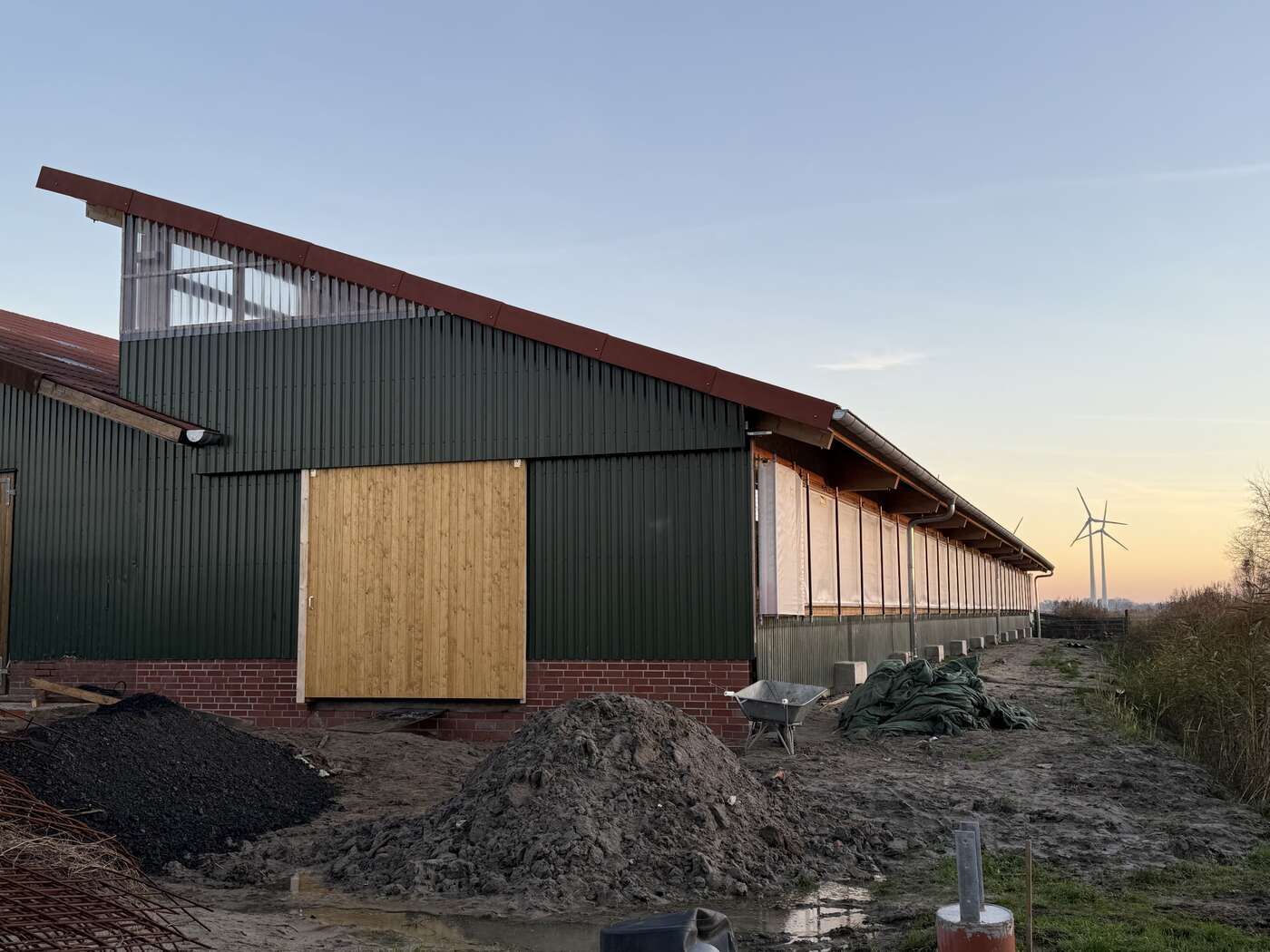 Es wird ein großes grünes Gebäude mit einer Holztür gebaut.