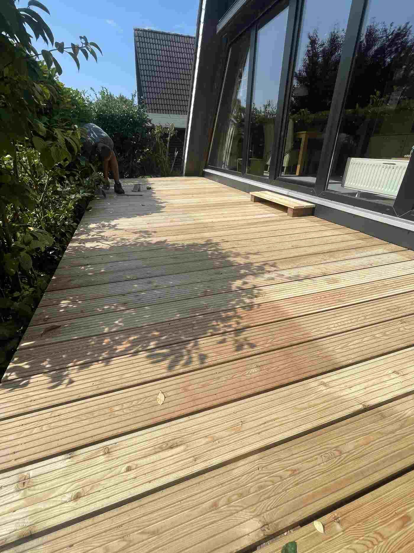 Vor einem Haus wird eine Holzterrasse gebaut.