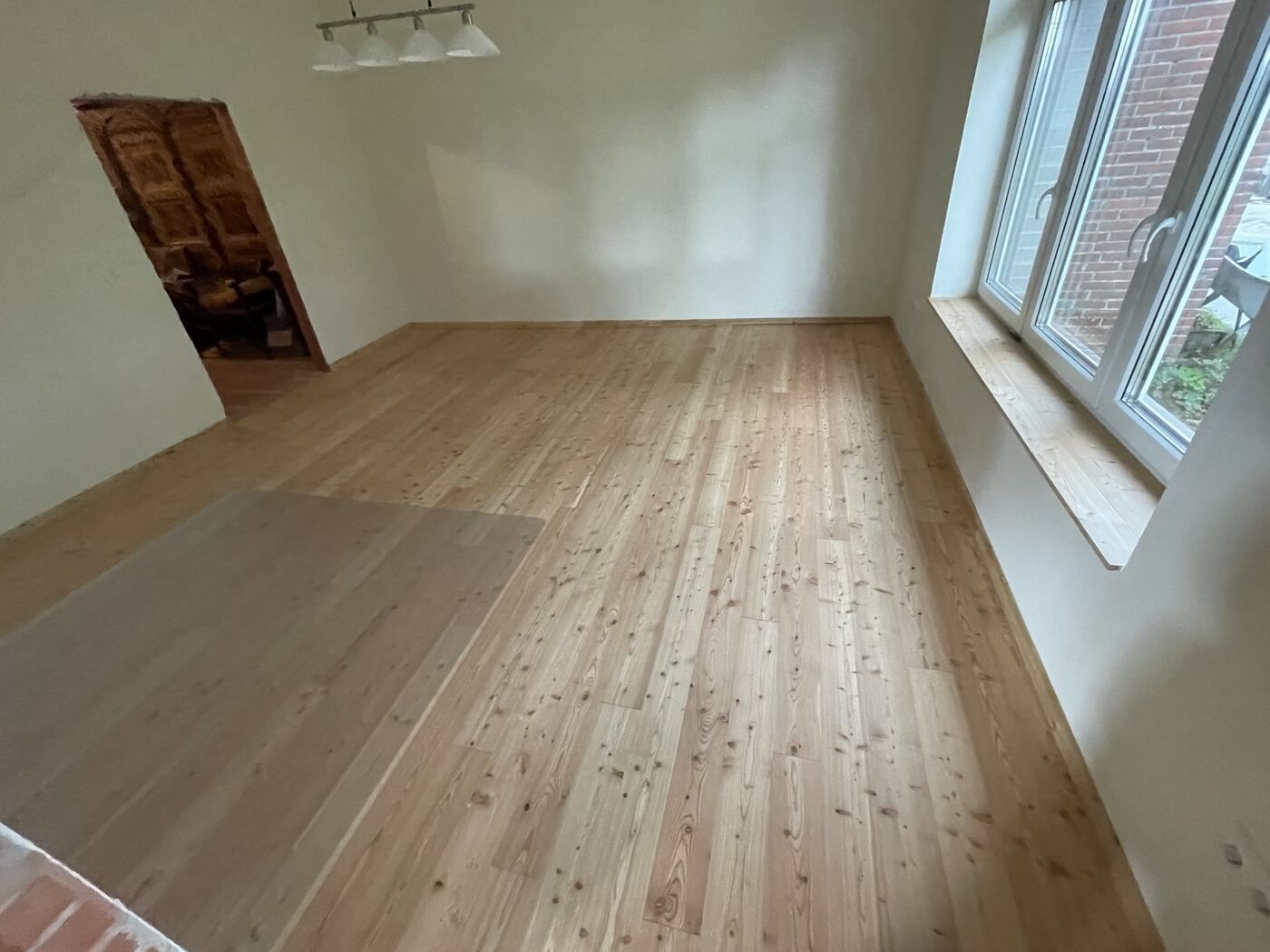 Ein Raum mit Holzboden und zwei Fenstern.