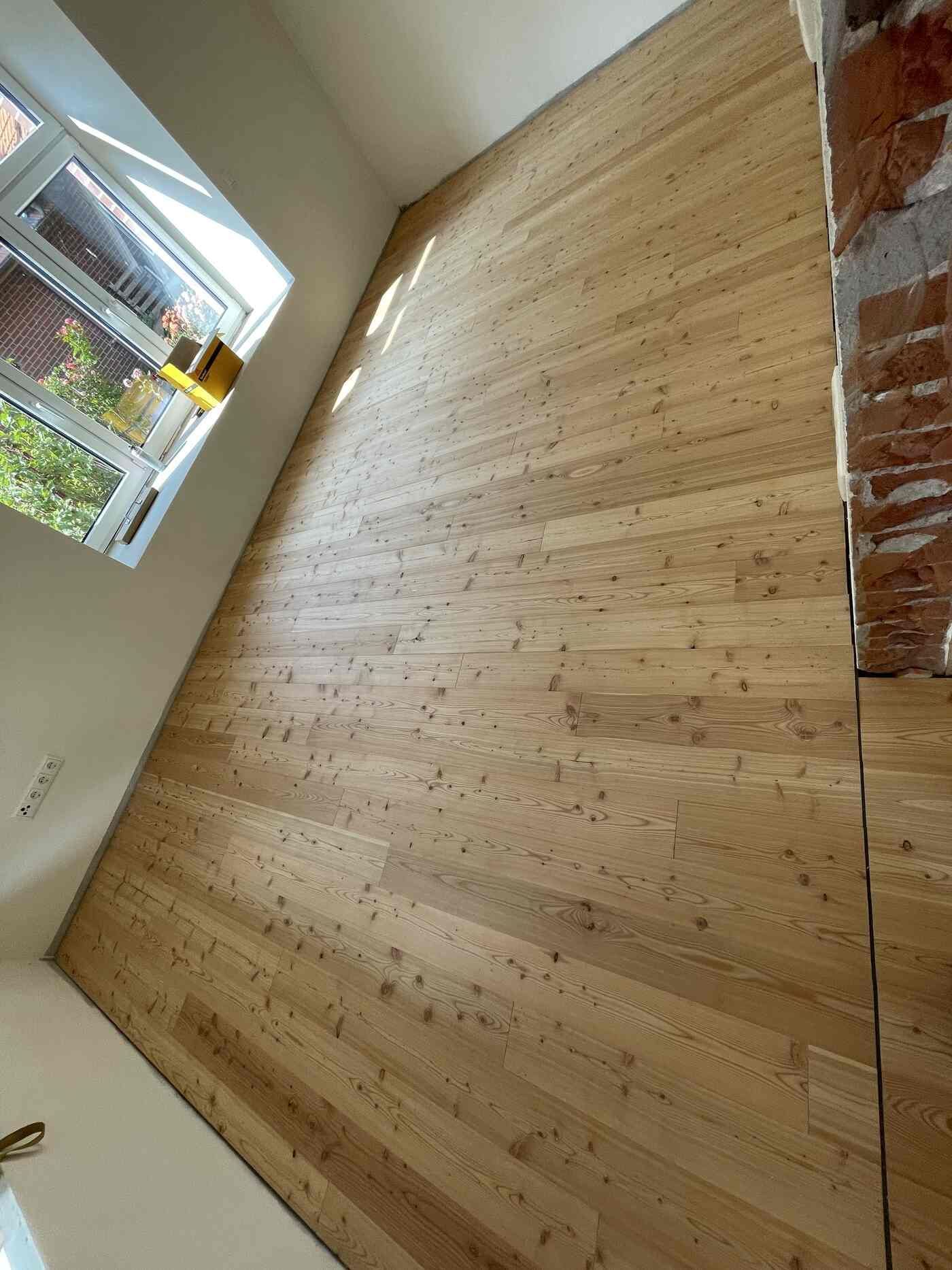 Ein Raum mit Holzboden und Fenster.