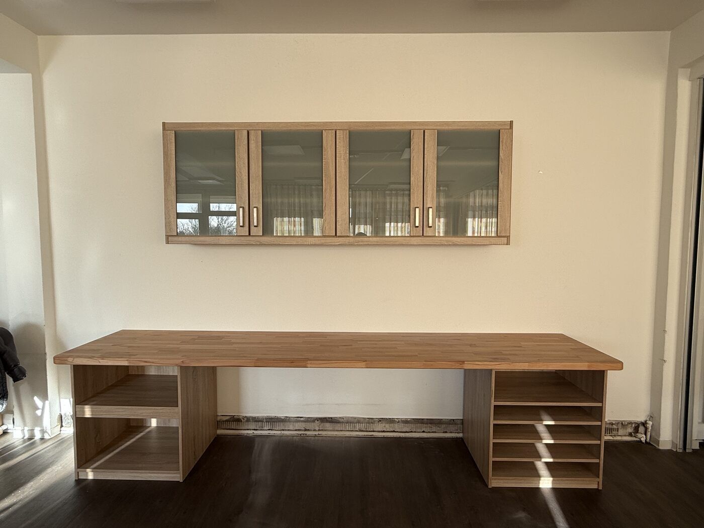 Ein Holzschreibtisch mit Glastüren und Regalen in einem Zimmer.