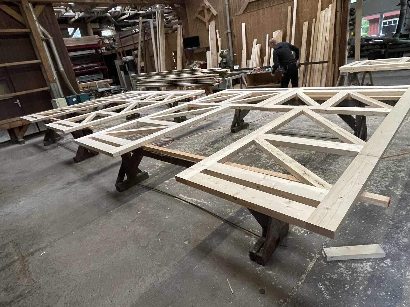 Ein Mann arbeitet in einer Werkstatt an einer Holzkonstruktion.