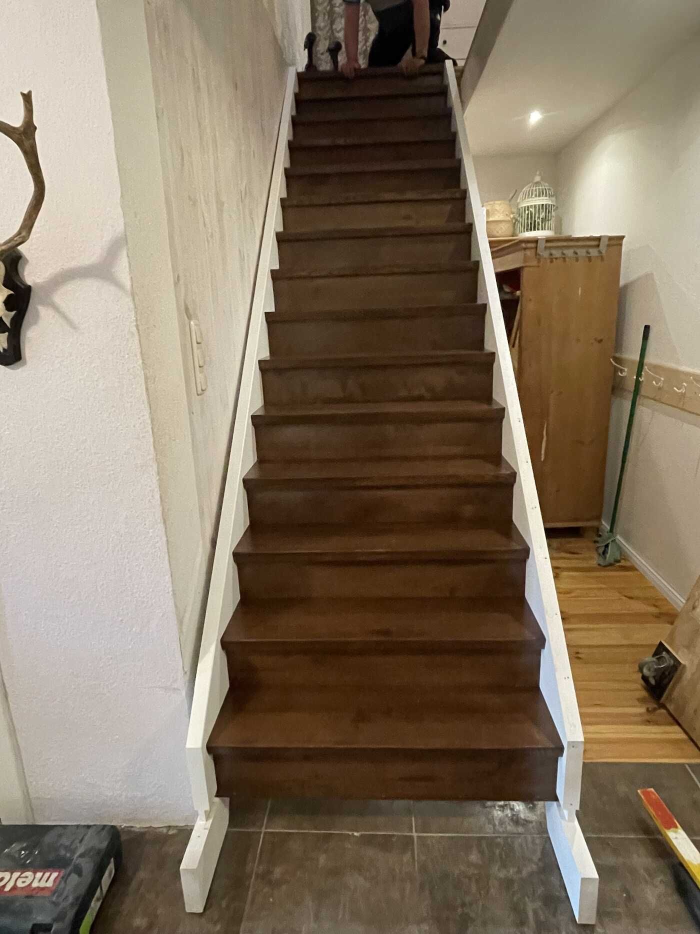 Eine Holztreppe mit einem weißen Geländer in einem Raum.