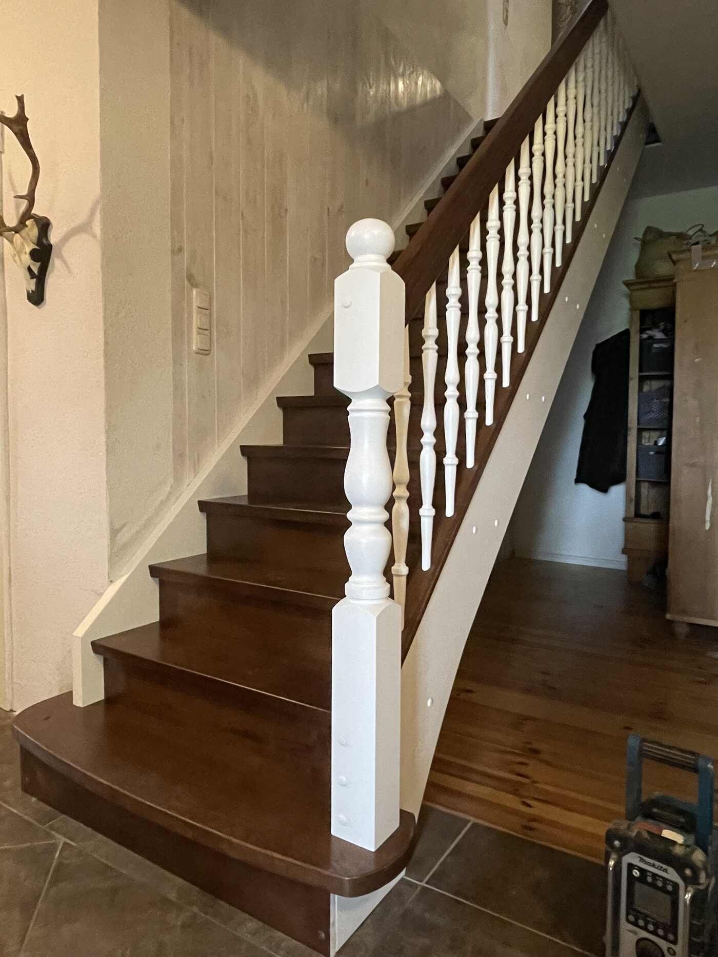 Eine Holztreppe mit einem weißen Geländer in einem Flur.